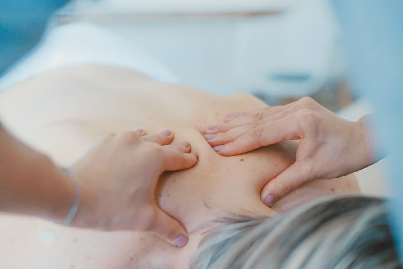 A therapist's hands working along a client's shoulder during a massage.